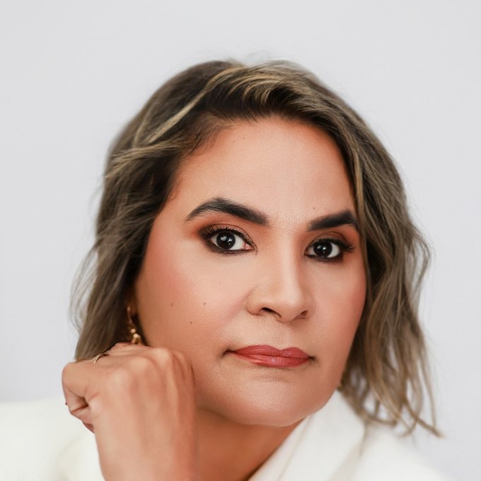 Warm portrait of Marlene Eggea smiling, hand resting on her chin.